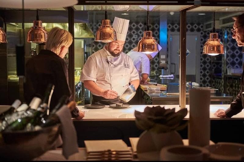 chef preparing food in front of people in an open kitchen