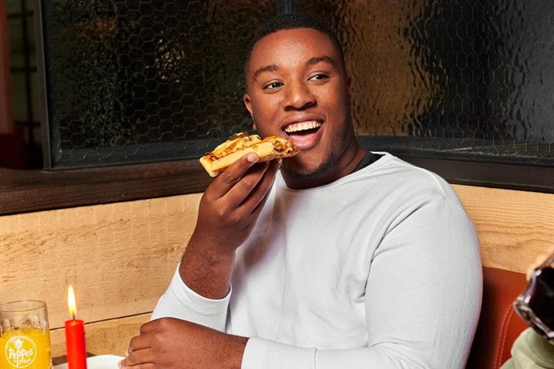 A guy eating a slice of pizza.